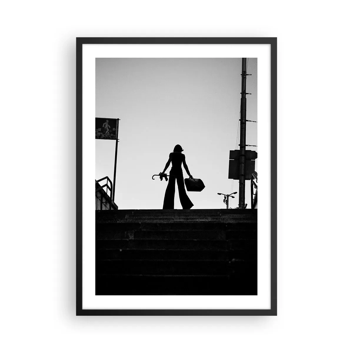 Plakát v černém rámu - Silueta ženy s kufrem na pozadí zapadajícího slunce - 50x70cm - Městská cesta - Moderní nástěnná dekorace do obývacího pokoje a ložnice ARTTOR
