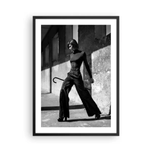 Plakát v černém rámu - Žena v elegantním oblečení s holí na pozadí strohé architektury - 50x70cm - Městská elegance - Moderní nástěnná dekorace do obývacího pokoje a ložnice ARTTOR