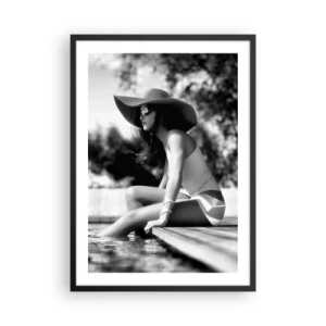 Plakát v černém rámu - Černobílá fotografie ženy v klobouku sedící u vody. - 50x70cm - Letní sen - Moderní nástěnná dekorace do obývacího pokoje a ložnice ARTTOR