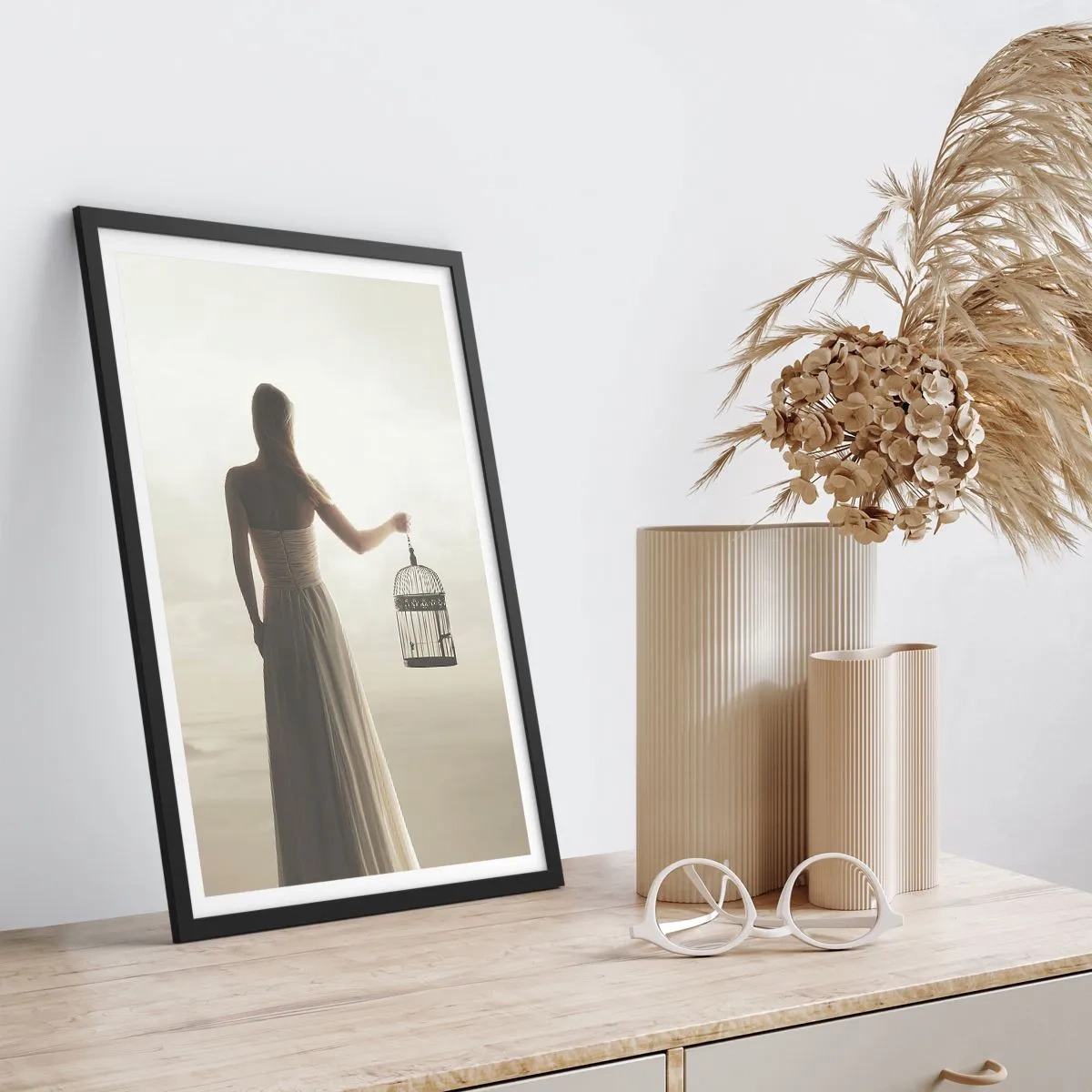 Plakát v černém rámu - Žena s klecí proti mlhavé krajině - 50x70cm - Buď svobodná - Moderní nástěnná dekorace do obývacího pokoje a ložnice ARTTOR