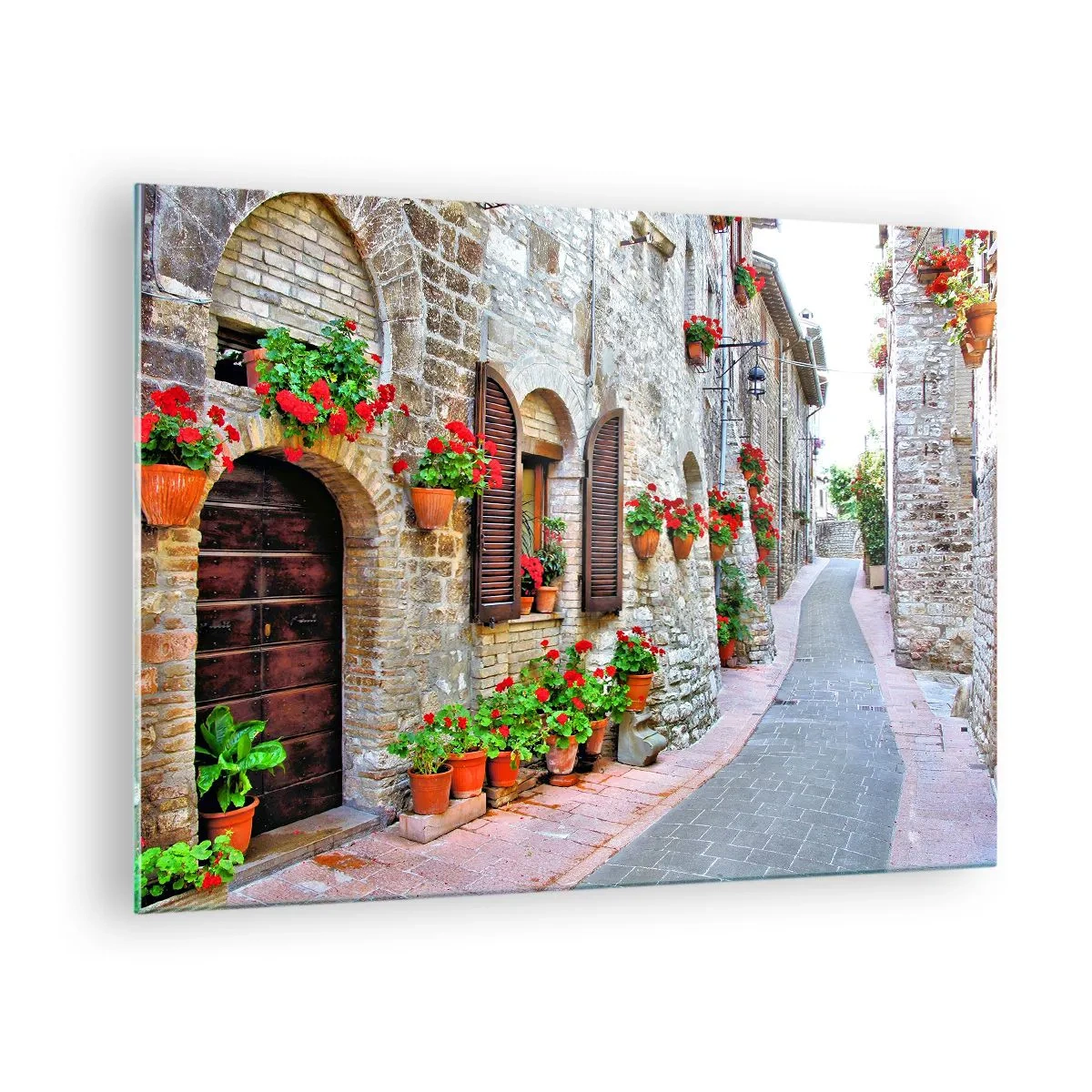 Obraz na skle - Malebná ulice s kamennými zdmi a červenými květinami - 70x50cm - Italská atmosféra - Moderní nástěnná dekorace do obývacího pokoje a ložnice ARTTOR